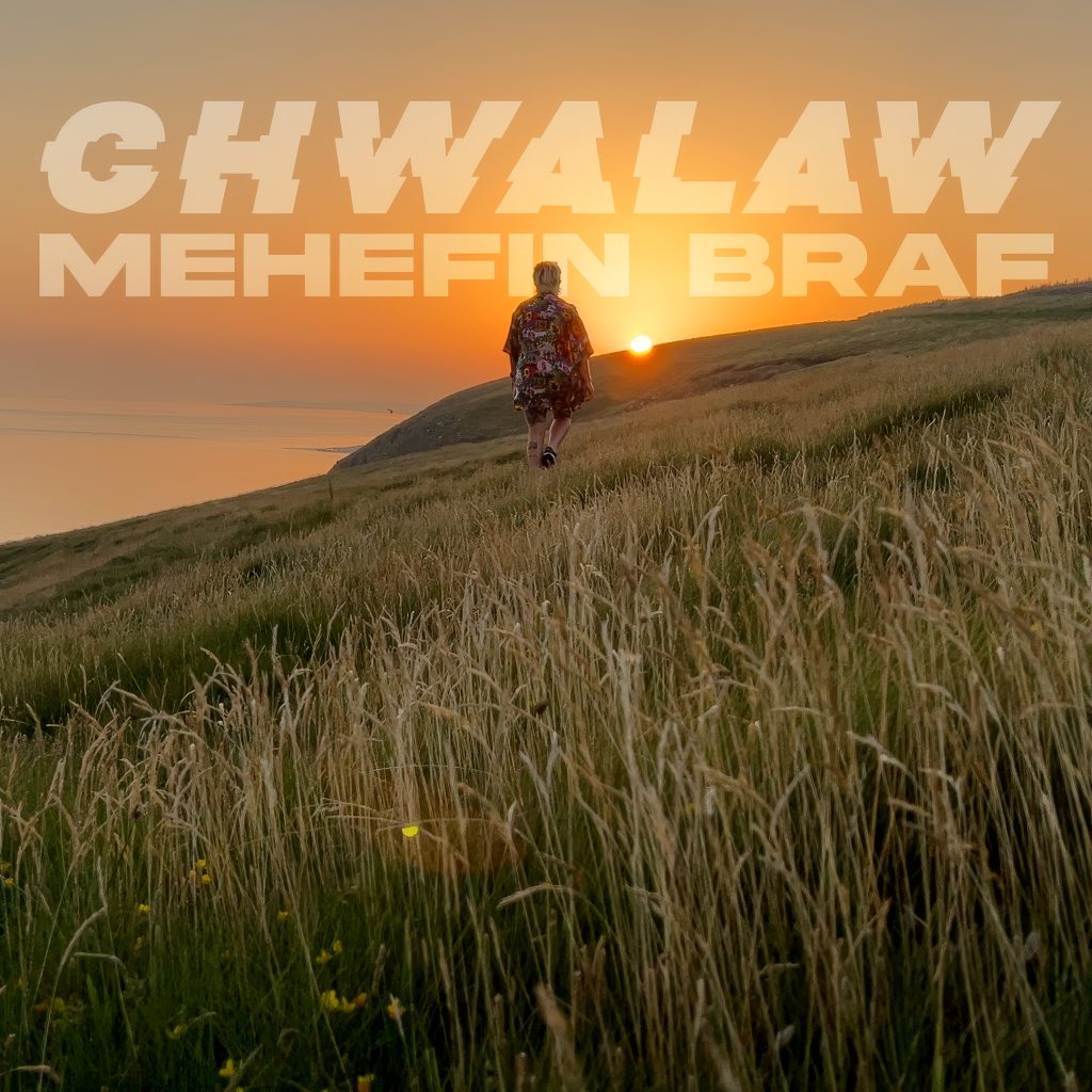 A photo of a woman walking away into the distance with the sun setting over a field. Rich in orange hues, with translucent text that reads 'Chwalaw - Mehefin Braf'